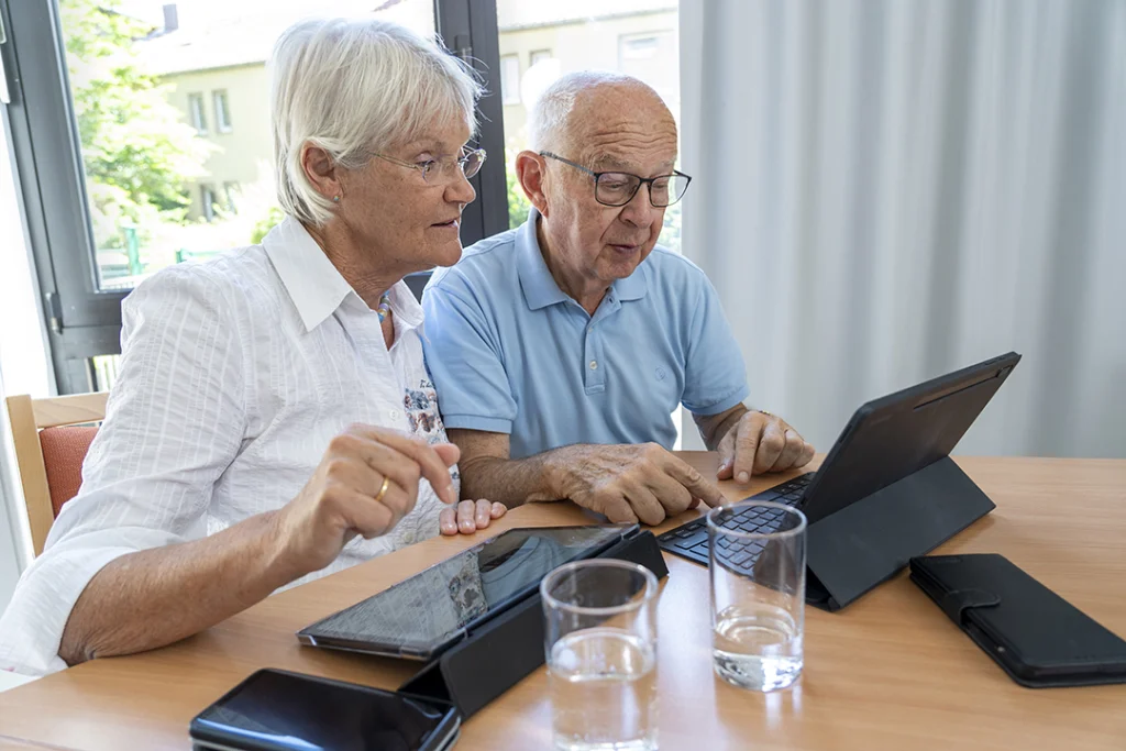 Eine Seniorin und ein Senior bedienen ein Tablet